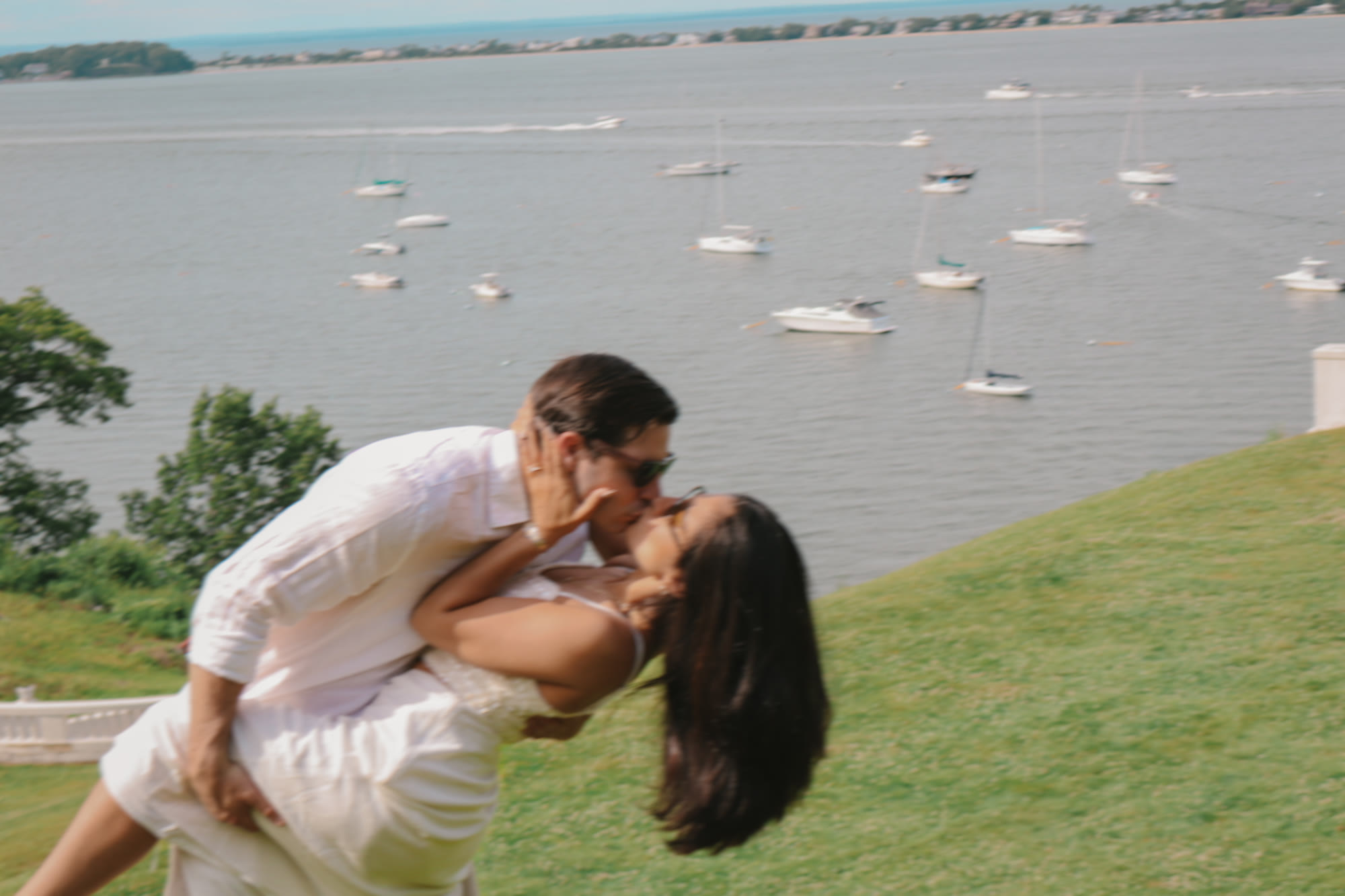 Couple kissing on green hill by harbor